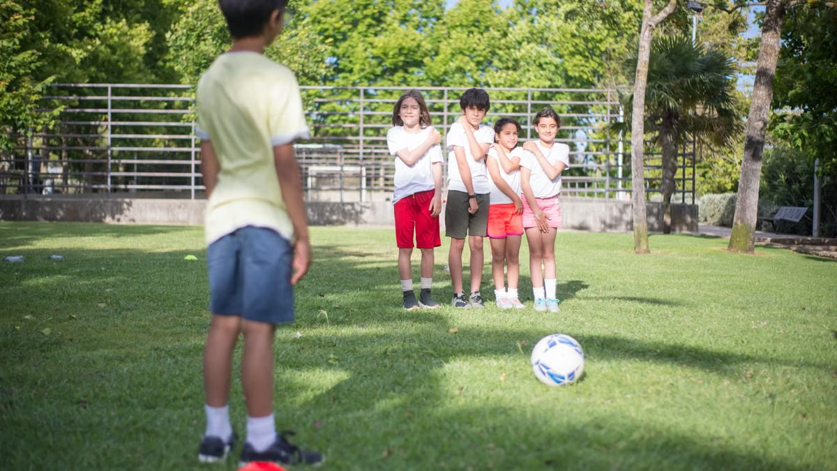 A group of kids enjoy a soccer game outdoors in a sunny park setting.